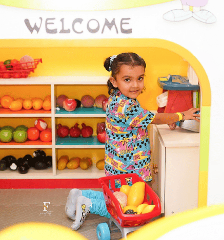 Child enjoying pretend shopping with a toy cart at Mio Wooray indoor play area.