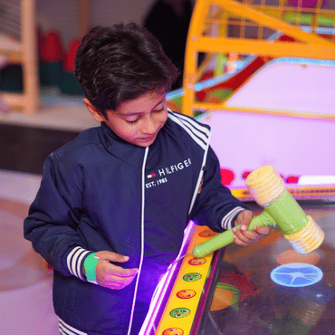 Child enjoying an interactive arcade game at Mio Wooray indoor play area.